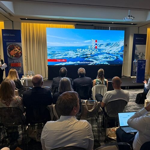 Publikum i sal og scene med presentasjon under sjømatseminar i Italia.