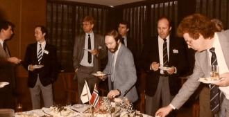 Nordmenn står rundt et bord, på bordet er det sushi. (1985)