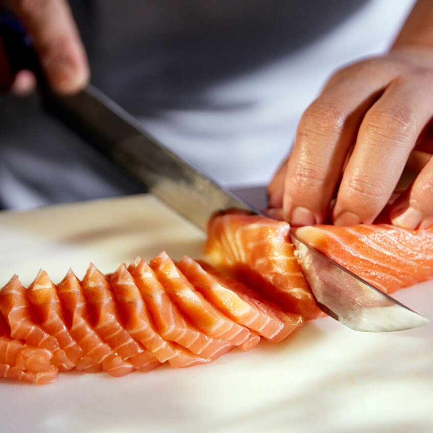 Kokk kutter opp sashimi av laksefilet